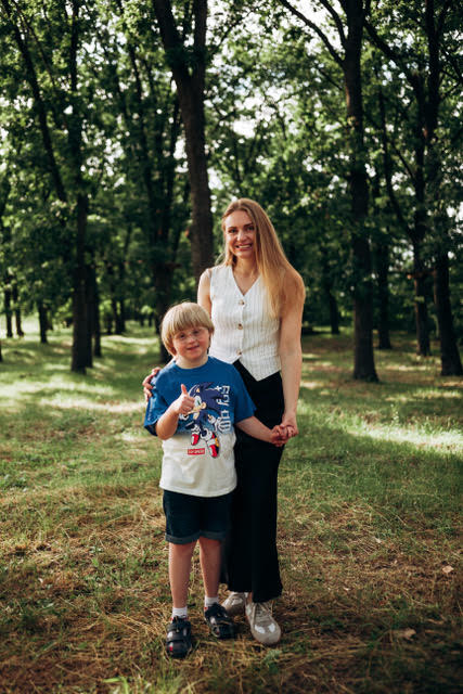 A mother and her son standing together among trees